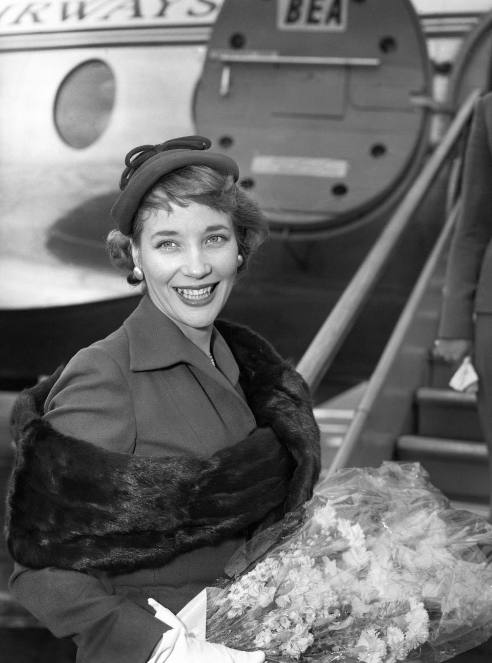 In this file photo dated July 1, 1957, Sylvia Syms prepares to leave London Airport for Berlin to attend the Film Festival, in which her picture 'Woman in a Dressing Gown' is being shown as the official British entry. Actress Sylvia Syms, who starred in classic British films including “Ice Cold in Alex” and “Victim,” has died, her family said Friday, Jan. 27, 2023. She was 89. (PA via AP)