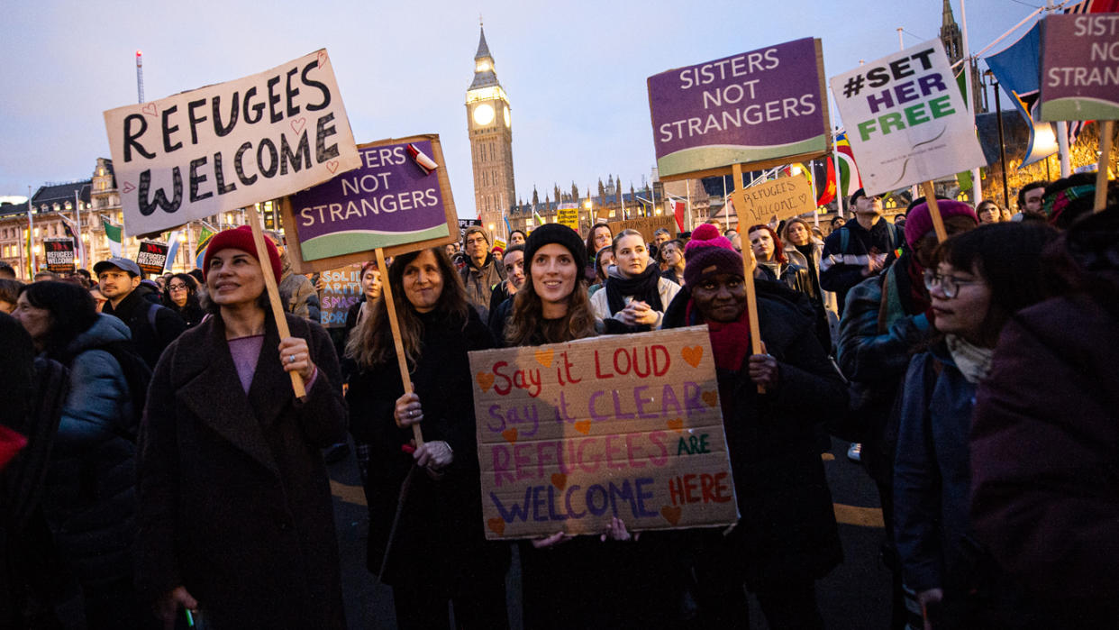 Hundreds of people stand near Big Ben with signs that read: Refugees welcome; Sisters, not strangers; and #setherfree.