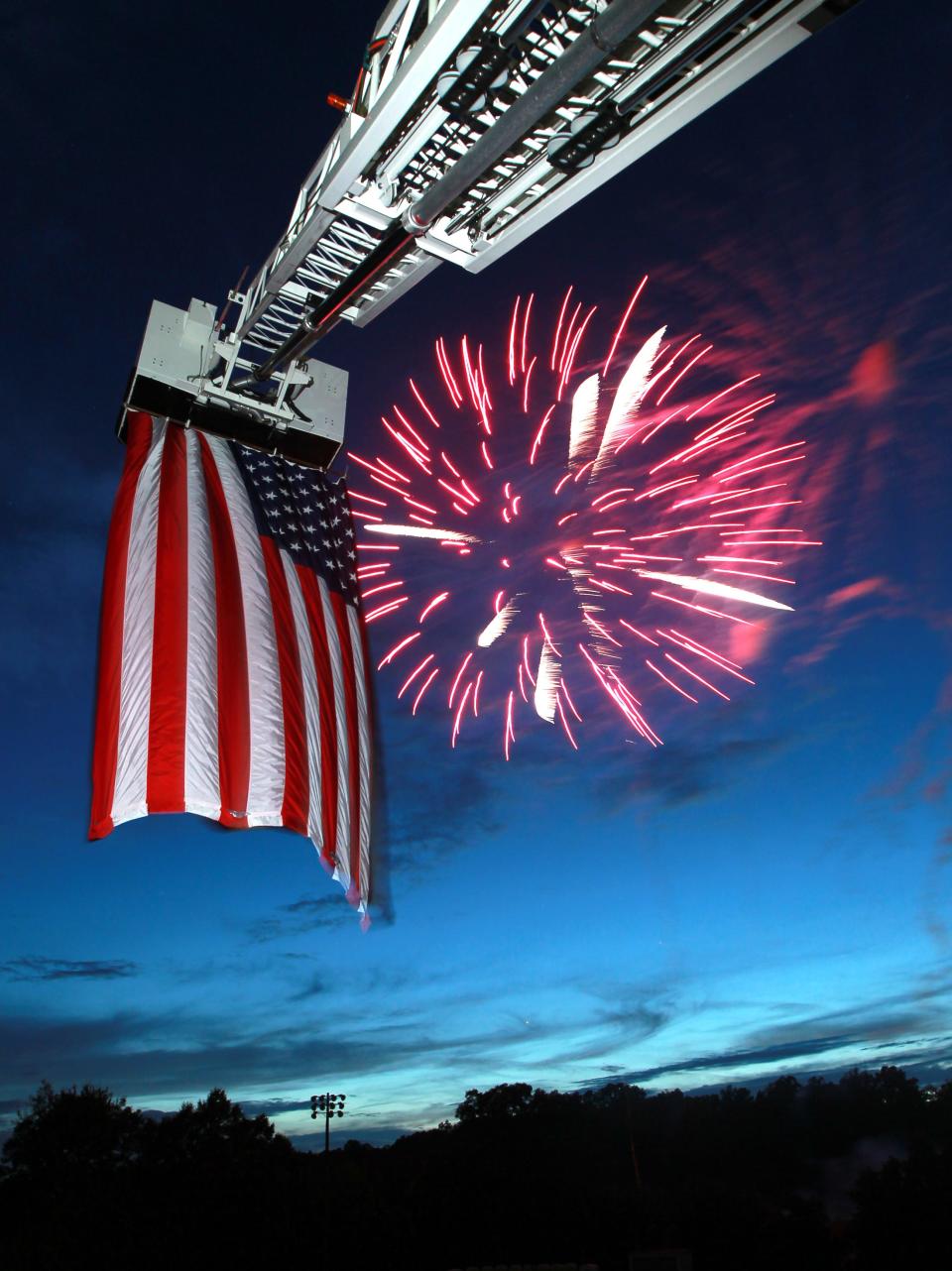 A burst of fireworks lights up the sky above a flag on a Seneca fire department ladder truck at Gignilliat Field in Seneca.