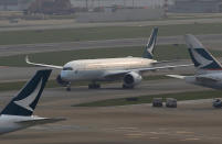 In this March 26, 2019 photo, a Cathay Pacific Airways passenger aircraft lands at the Hong Kong International Airport. Cathay Pacific Airways is acquiring Hong Kong-based budget airline HK Express. Cathay said Wednesday, March 27, 2019, it will pay 4.93 billion Hong Kong dollars ($628 million) for HK Express. It said the acquisition will retain its identity as a separate brand and be operated as a low-cost carrier. (AP Photo/Kin Cheung)