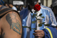 A mourner, sporting a tattoo of Diego Maradona on his forearm, waits in line to pay his final respects to the Argentine soccer great who died from a heart attack, in Buenos Aires, Argentina, Thursday, Nov. 26, 2020. Maradona’s wooden casket was in the main lobby of the presidential office, covered in an Argentine flag and a No. 10 national team jersey. (AP Photo/Rodrigo Abd)
