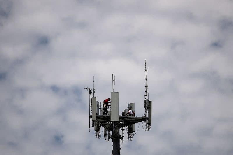 FILE PHOTO: Workers install 5G telecommunications equipment on a T-Mobile tower in Seabrook, Texas