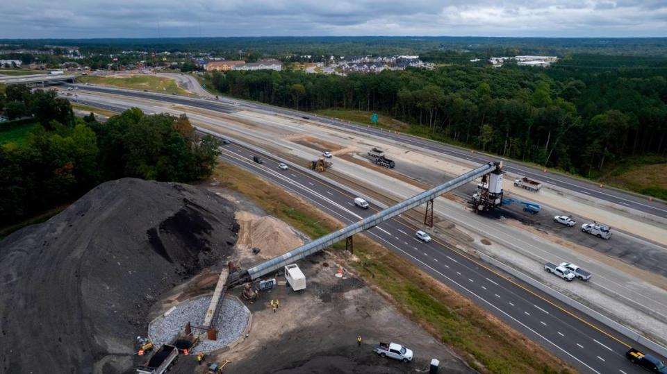 A conveyor system carries asphalt over the eastbound lanes of I-40 near the N.C. 42 interchange in Garner on Wednesday, Sept. 27, 2023. The conveyor will move about 175,000 tons of asphalt from its plant off Cleveland Road in the coming months, enough to pave 5 miles of eight-lane highway.