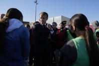 French President Emmanuel Macron, center, meets youth on a stadium in Tremblay-en-France, outside Paris, Thursday, Oct.14, 2021. French President Emmanuel Macron will promote sports ahead of the 2024 Olympic Games in Paris. (AP Photo/Francois Mori, Pool)