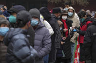 A volunteer wearing a face mask to help protect from the coronavirus checks the name list as residents line up during a mass coronavirus testing at a school in Fengtai District in Beijing, Monday, Jan. 24, 2022. Chinese authorities have lifted a monthlong lockdown of Xi'an and its 13 million residents as infections subside ahead of the Winter Olympics. Meanwhile, the 2 million residents of one Beijing district are being tested following a series of cases in the capital. (AP Photo/Andy Wong)