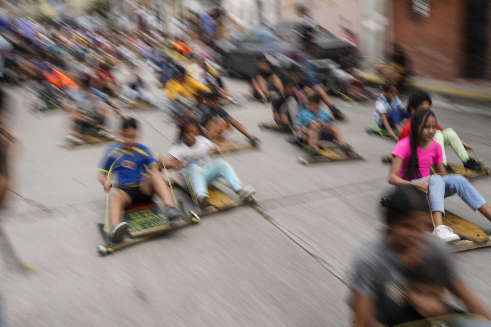 Children compete in the traditional street wooden go kart race known as "carruchas", as part of the Epiphany celebrations in Caracas, Venezuela, Saturday, Jan. 6, 2024. (AP Photo/Matias Delacroix)