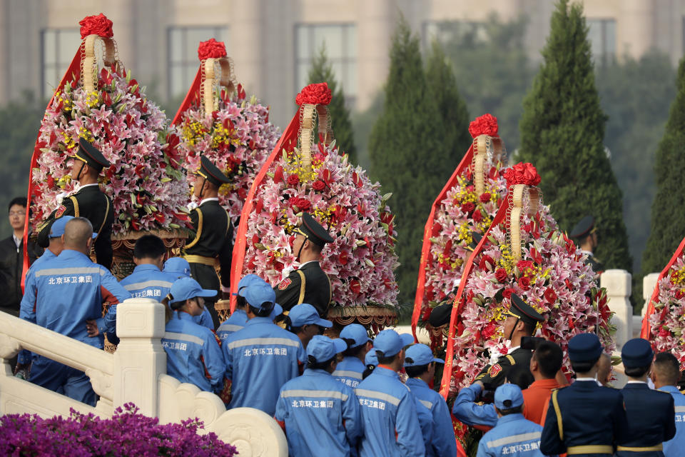 Sanitation workers watch as members of a Chinese honor guard carry floral wreaths up the steps of the Monument to the People's Heroes before a ceremony to mark Martyr's Day at Tiananmen Square in Beijing, Monday, Sept. 30, 2019, ahead of a massive celebration of the People's Republic's 70th anniversary. (AP Photo/Mark Schiefelbein, Pool)