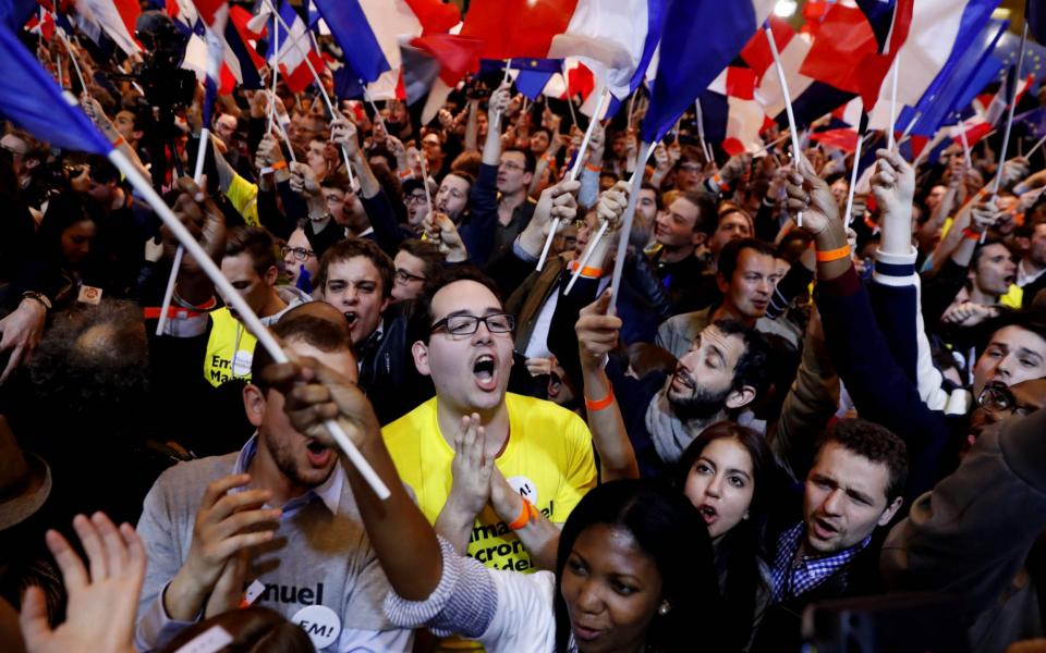 Emmanuel Macron's supporters cheer following the announcement he was on course to qualify for the second round - Credit: PATRICK KOVARIK/AFP