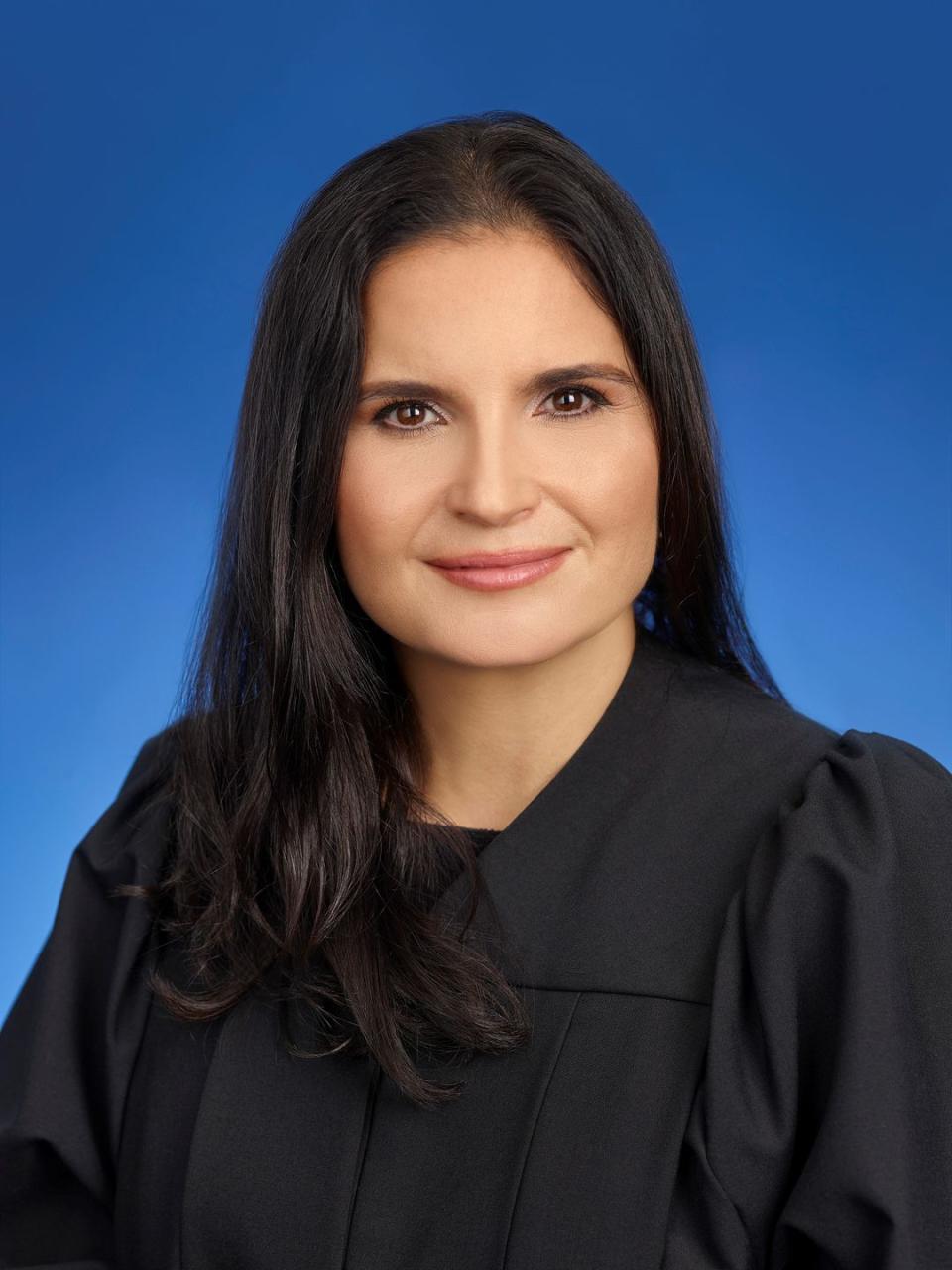 aileen cannon, wearing black judge robes, looking straight ahead at the camera, with a blue backdrop behind her