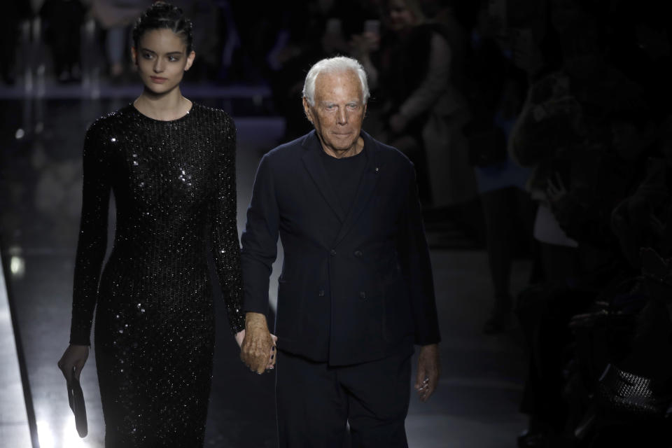 Designer Giorgio Armani, right, accepts applause as he walks with a model after the Giorgio Armani women's Fall-Winter 2019-2020 collection, that was presented in Milan, Italy, Saturday, Feb. 23, 2019. (AP Photo/Luca Bruno)