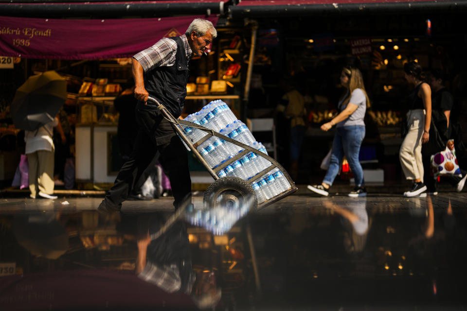 A man pushes a trolley with bottles of water on a hot summer day, in Istanbul, Turkey, Thursday, July 13, 2023. (AP Photo/Francisco Seco)