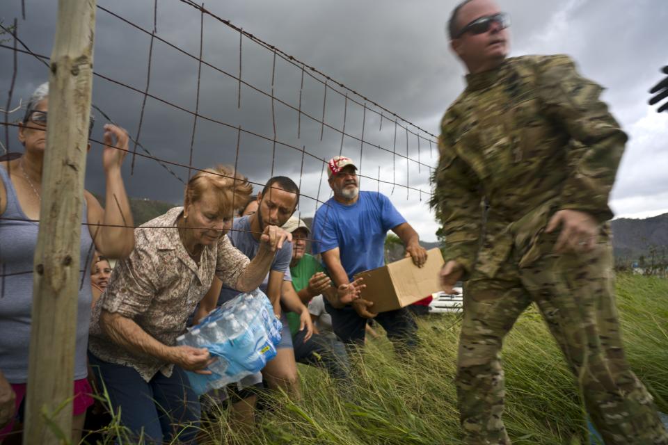 FILE - In this Oct. 7, 2017 file photo, a Puerto Rican National Guard delivers food and water brought by helicopter in the San Lorenzo neighborhood of Morovis, Puerto Rico, two weeks after Hurricane Maria hit. Puerto Rico was understocked in food and fresh water in part because Hurricane Irma struck two weeks before Maria, battering the U.S. Virgin Islands. Staff was depleted because of wildfires and other major natural disasters. (AP Photo/Ramon Espinosa, File)