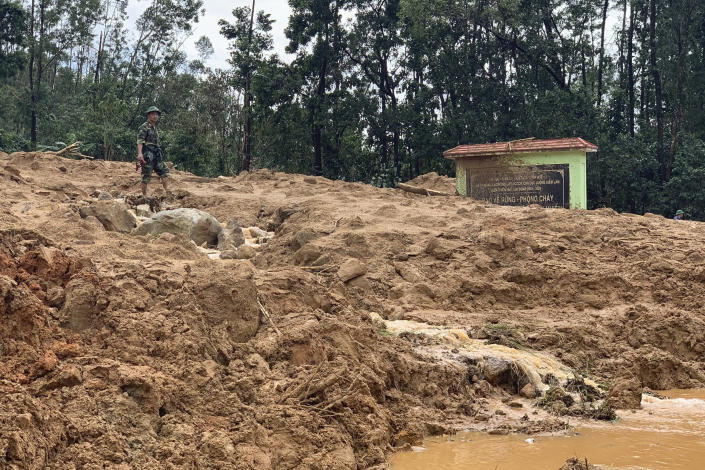 An army officer stands at the site of a landslide at a forest ranger outpost in Thua Thien-Hue province, Vietnam, Thursday, Oct. 15, 2020. Rescuers recovered the bodies of 11 army personnel and two other people who were buried in the landslide while trying to reach victims of another landslide, state media reported Friday, Oct. 16, 2020. (Tran Le Lam/VNA via AP)