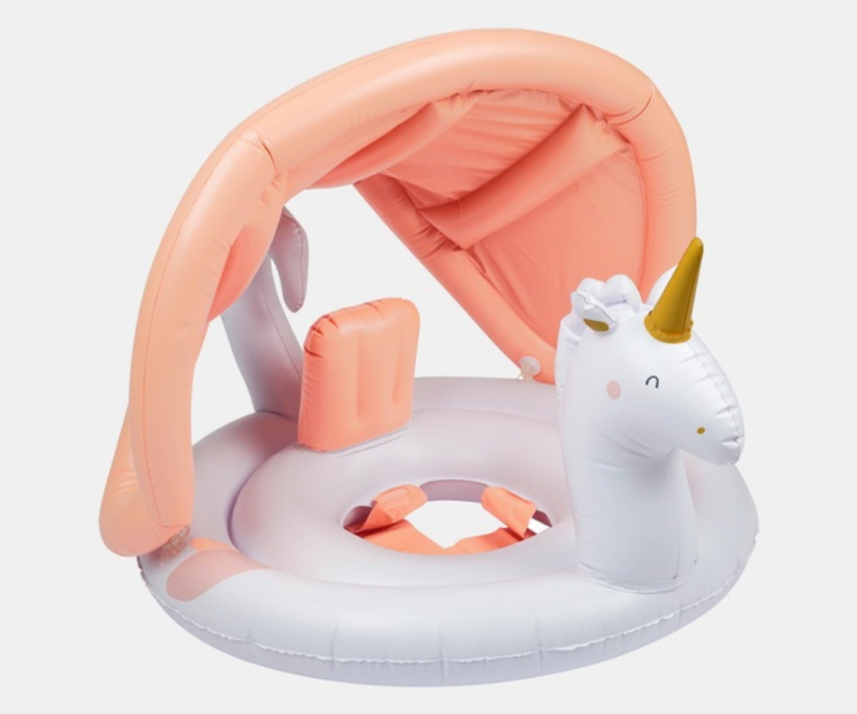 A white inflatable baby ring with a peach canopy and a white Unicorn head with a gold horn against a white background.