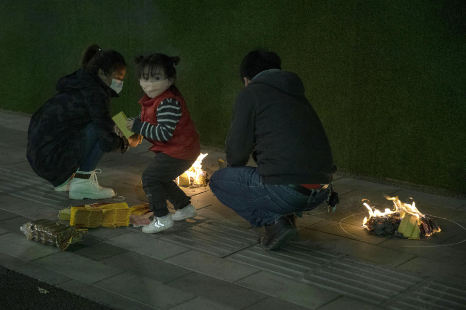 A family burn paper offerings for their departed relatives on the streets of Wuhan in central China's Hubei province on Saturday, April 4, 2020. Authorities are controlling access and limiting the number of people entering cemeteries across China during the annual Qingming festival, also known as the Grave Sweeping Day, a day when Chinese around the world remember their dearly departed and take time off to clean up the tombs and place flowers and offerings, a move to prevent the spread of the new coronavirus outbreak. (AP Photo/Ng Han Guan)