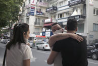 A man wearing a face mask to protect against the spread of coronavirus, embraces a friend in city the centre, in Ankara, Turkey, Sunday, June 21, 2020. Turkish authorities have made the wearing of masks mandatory in three major cities to curb the spread of COVID-19 following an uptick in confirmed cases since the reopening of many businesses.(AP Photo/Burhan Ozbilici)