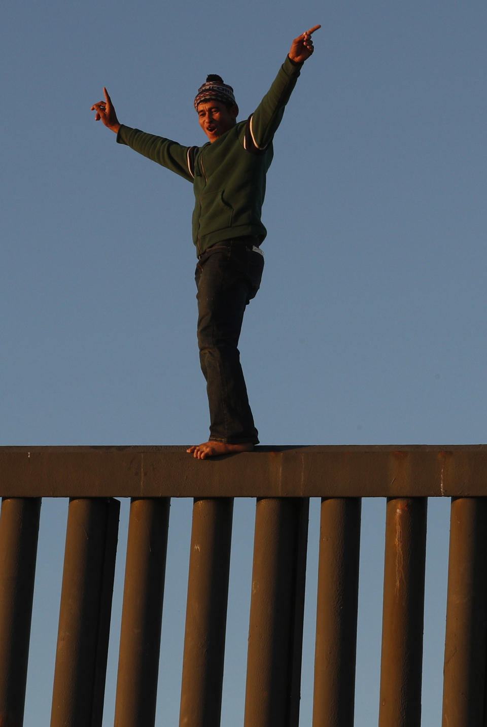 Honduran migrant Jonatan Matamoros Flores, 33, who arrived with an October migrant caravan, stands atop the U.S. border wall briefly at sunset, before returning to the Mexican side, in Tijuana, Mexico, Saturday, Dec. 8, 2018. (AP Photo/Rebecca Blackwell)