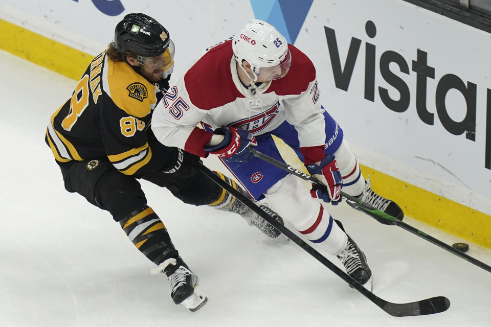 Boston Bruins right wing David Pastrnak and Montreal Canadiens right wing Denis Gurianov (25) vie for the puck during the first period of an NHL hockey game, Thursday, March 23, 2023, in Boston. (AP Photo/Steven Senne)