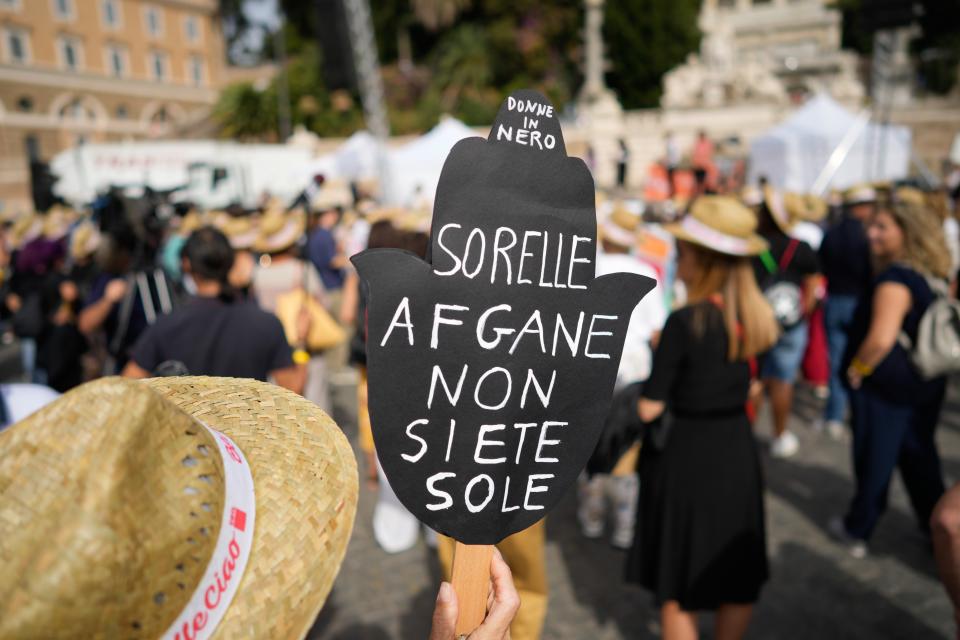 A woman holds a banner reading "Afghan sisters you're not alone" during a demonstration in favor of Afghan women's rights, staged by women rights activists, in Rome, Saturday, Sept. 25, 2021. (AP Photo/Andrew Medichini)