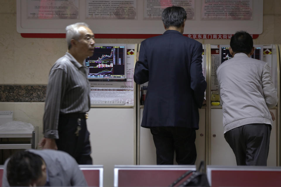 A man walks by investors check stock prices at a brokerage house in Beijing, Wednesday, April 24, 2019. Shares were mostly lower in Asia on Wednesday despite the S&P 500’s all-time record high close the day before. (AP Photo/Andy Wong)
