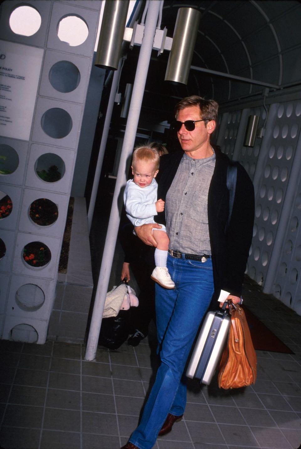 <p>In 1988 Harrison Ford was photographed making his way through the airport with one very important carry-on; his son, Malcom. </p>