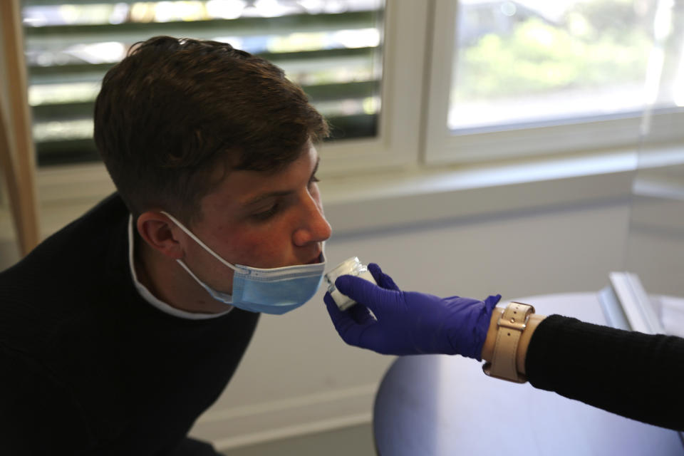 Evan Cesa, a patient, smells a small pot of fragrance during tests in a clinic in Nice, France, on Monday, Feb. 8, 2021, to help determine how his sense of smell and taste have been degraded since he contracted COVID-19 in September 2020. A year into the coronavirus pandemic, doctors are striving to better understand and treat patients who lose their sense of smell. (AP Photo/John Leicester)