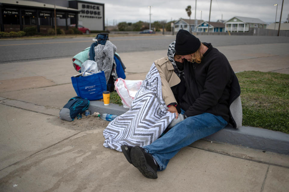 Image: Couple sit amongst belongings as they embrace to keep warm in Galveston, Texas (Adrees Latif / Reuters)