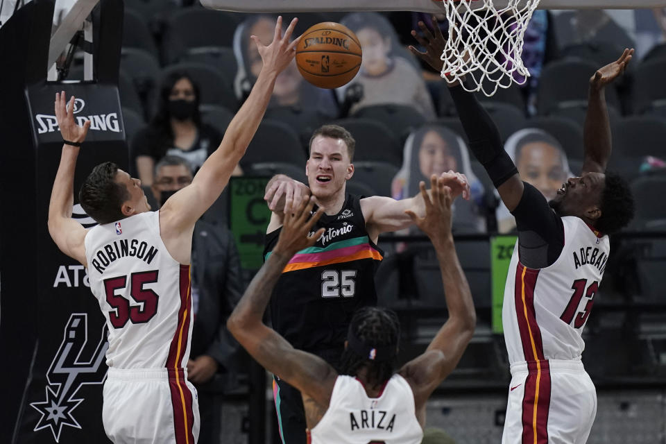 San Antonio Spurs center Jakob Poeltl (25) passes the ball as he is pressured by Miami Heat defenders Duncan Robinson (55), Trevor Ariza (8) and Bam Adebayo (13) during the second half of an NBA basketball game in San Antonio, Wednesday, April 21, 2021. (AP Photo/Eric Gay)