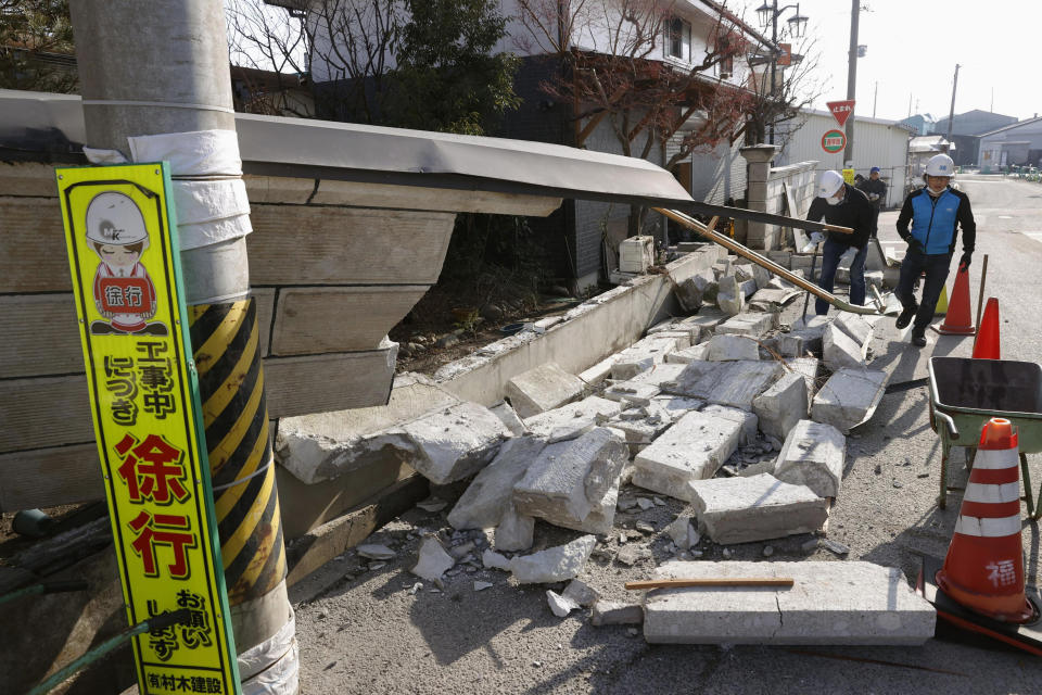 Men help clean debris after the wall of a house collapsed in Kunimi town, north of Fukushima city, northeastern Japan, Sunday, Feb. 14, 2021, following an earthquake Saturday. Residents in northeastern Japan on Sunday are cleaning up clutter in stores and homes after the strong earthquake set off a landslide on a highway, stopped trains and caused power blackouts for thousands of people. (Jun Hirata/Kyodo News via AP)