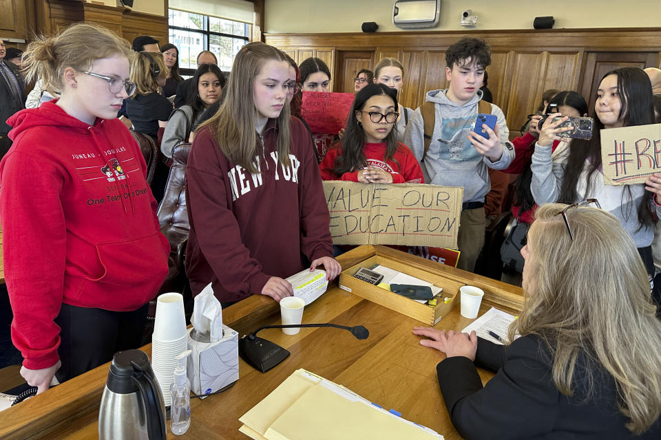 Meadow Stanley, far left, and Rachel Wood, second from left, are among the students speaking, Thursday, April 4, 2024, in Juneau, Alaska, with state Rep. Julie Coulombe about why she did not vote to override the governor's veto of an education package last month. The students were part of an organized walkout Thursday to protest Alaska Gov. Mike Dunleavy's veto and the Legislature's failure to override it. (AP Photo/Becky Bohrer)