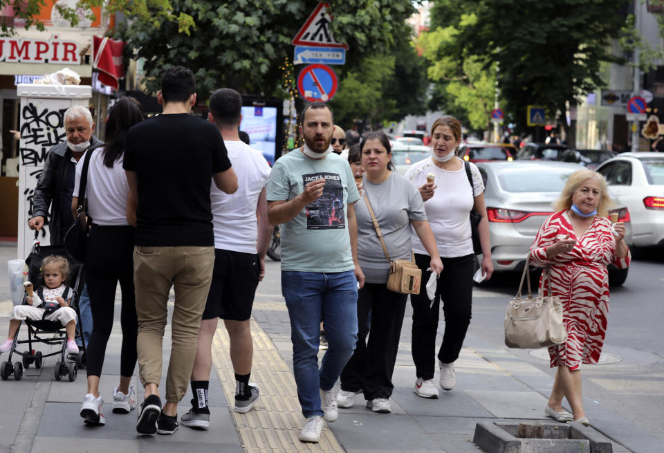 People who are not wearing face masks to protect against the spread of coronavirus, walk in city the centre, in Ankara, Turkey, Sunday, June 21, 2020. Turkish authorities have made the wearing of masks mandatory in three major cities to curb the spread of COVID-19 following an uptick in confirmed cases since the reopening of many businesses.(AP Photo/Burhan Ozbilici)