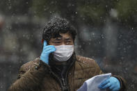 A goverment worker wearing a face mask talks on the phone as he waits for patients to arrive at a tumor hospital newly designated to treat COVID-19 patients in Wuhan in central China's Hubei Province, Saturday, Feb. 15, 2020. China reported 143 virus deaths and a dip in new cases Saturday while the government announced new anti-disease measures as businesses reopen following sweeping controls that idled much of the economy. (Chinatopix via AP)