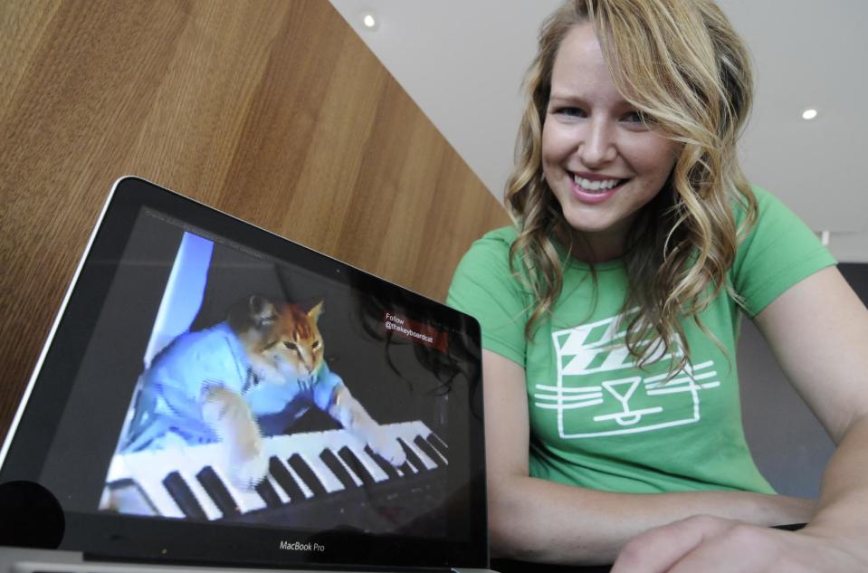 FILE - In this Wed., Aug. 29, 2012 file photo, Katie Hill, a program associate with the Walker Art Center, shows a frame from a cat video of a cat playing the piano, in Minneapolis. The Walker presented its first "Internet Cat Video Film Festival" to showcase the best in filmed feline hijinks that drew a crowd of more than 10,000 people. 80 videos culled from 10,000 submissions that covered the simple, funny moment to polished animations and kitty works made by trained filmmakers were shown to the public for free. (AP Photo/Jim Mone, File)