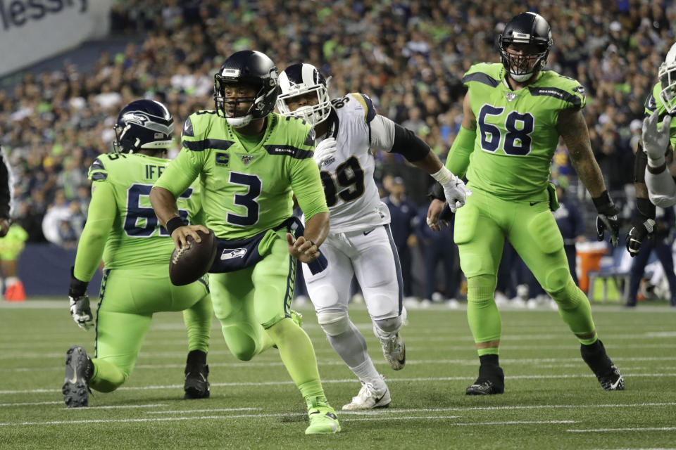 Seattle Seahawks quarterback Russell Wilson (3) scrambles before making a short pass to running back Chris Carson for a touchdown against the Los Angeles Rams during the second half of an NFL football game Thursday, Oct. 3, 2019, in Seattle. (AP Photo/Elaine Thompson)