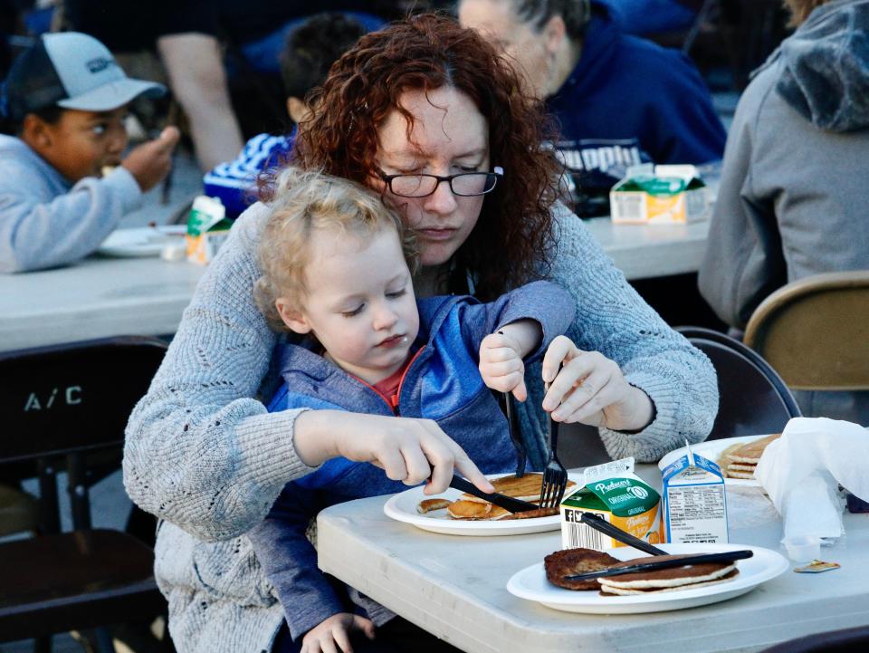 Courtney Parker of Redding helps son Logan Nunes cut his pancakes during the Asphalt Cowboys' well-attended breakfast on Friday morning, May 20, 2022, along the Market Street Promenade in downtown Redding.