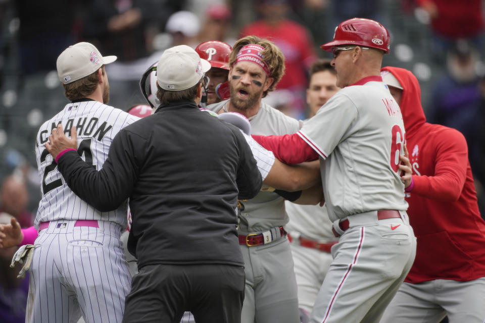 Philadelphia Phillies designated hitter Bryce Harper, back center, is held back from pursuing Colorado Rockies relief pitcher Jake Bird by, from front left, Colorado's Ryan McMahon, first base umpire Ben May and Philadelphia third base coach Dusty Wathan in the seventh inning of a baseball game, Sunday, May 14, 2023, in Denver. (AP Photo/David Zalubowski)