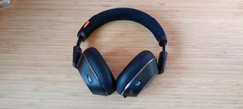 A pair of Poly Voyager 8200 UC headphones on a wooden desk