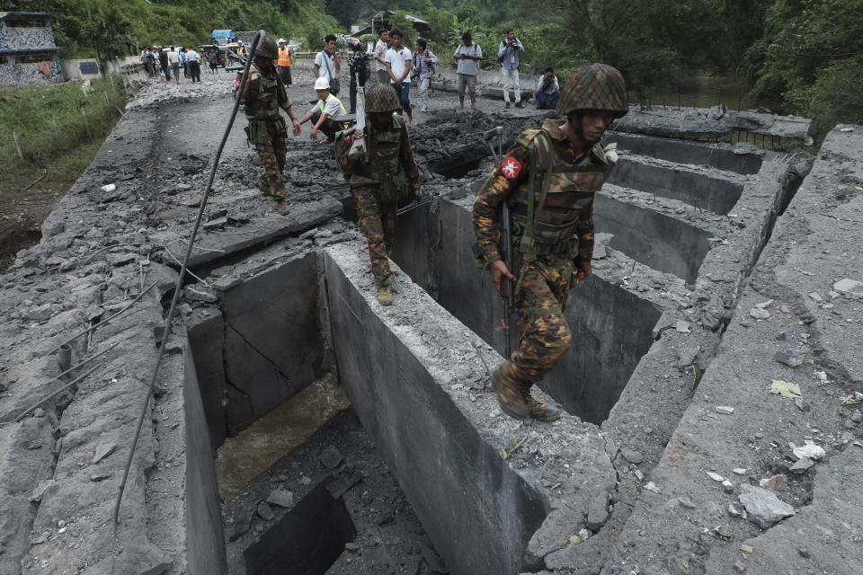 Soldiers walk over Gote Twin bridge damaged by explosion Thursday, Aug. 15, 2019, in Gote Twin, Naung Cho township, northern Shan State, Myanmar. Members of an ethnic rebel alliance in Myanmar staged coordinated attacks in five locations Thursday in Mandalay Region and in northern Shan State, where 14 people were reported killed. The group said the attacks were a response to government military operations in territory where the Kokang, Ta-ang and Rakhine minorities live. (AP Photo/Pyae Sone Aung)