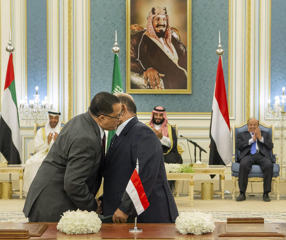 In this photo released by the Saudi Royal Palace, Yemeni Southern Transitional Council member and former Aden Governor Nasser al-Khabji, left, and Yemen’s deputy Prime Minister Salem al-Khanbashi greet each other before signing a power-sharing deal witnessed by Yemen's president, Abed Rabbo Mansour Hadi, background right, Saudi Arabia's Crown Prince Mohammed bin Salman, center, and Dhabi's Crown Prince, Mohammed bin Zayed Al Nahyan, in Riyadh, Saudi Arabia, Tuesday, Nov. 5, 2019. Yemen's internationally recognized government signed a power-sharing deal with Yemeni separatists that are backed by the United Arab Emirates. A picture of Saudi Arabia's founder late King Abdul Aziz Al Saud hangs on wall. (Bandar Aljaloud/Saudi Royal Palace via AP)