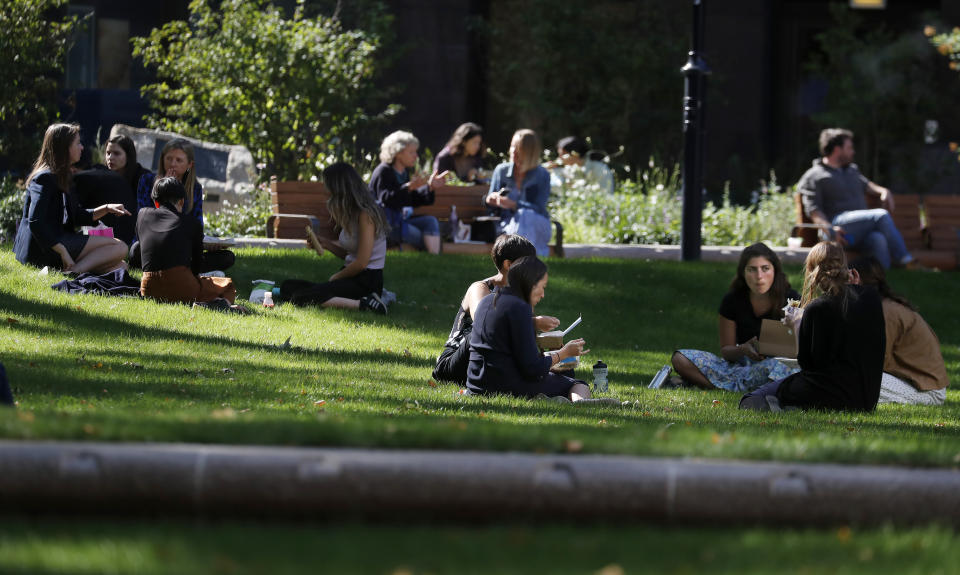 People eat lunch in a park in London, Monday, Sept. 21, 2020. Britain's top medical advisers have painted a grim picture of exponential growth in illness and death if nothing is done to control the second wave of coronavirus infections, laying the groundwork for the government to announce new restrictions later this week. (AP Photo/Frank Augstein)