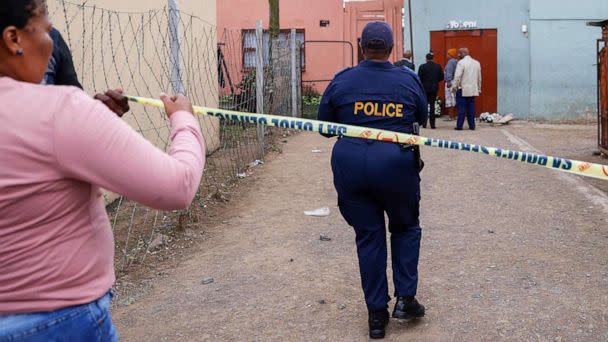 PHOTO: South African Police Services members use a tape to cordon off the entrance of a township pub in southern city of East London on July 5, 2022, after the death of 21 teenagers in the establishment. (Phill Magakoe/AFP via Getty Images)