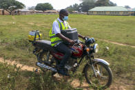 Yunusa Bawa, a community health worker, rides on a motorbike with a box of AstraZeneca coronavirus vaccines, in Sabon Kuje on the outskirts of Abuja, Nigeria, Monday, Dec 6, 2021. As Nigeria tries to meet an ambitious goal of fully vaccinating 55 million of its 206 million people in the next two months, health care workers in some parts of the country risk their lives to reach the rural population. (AP Photo/Gbemiga Olamikan)