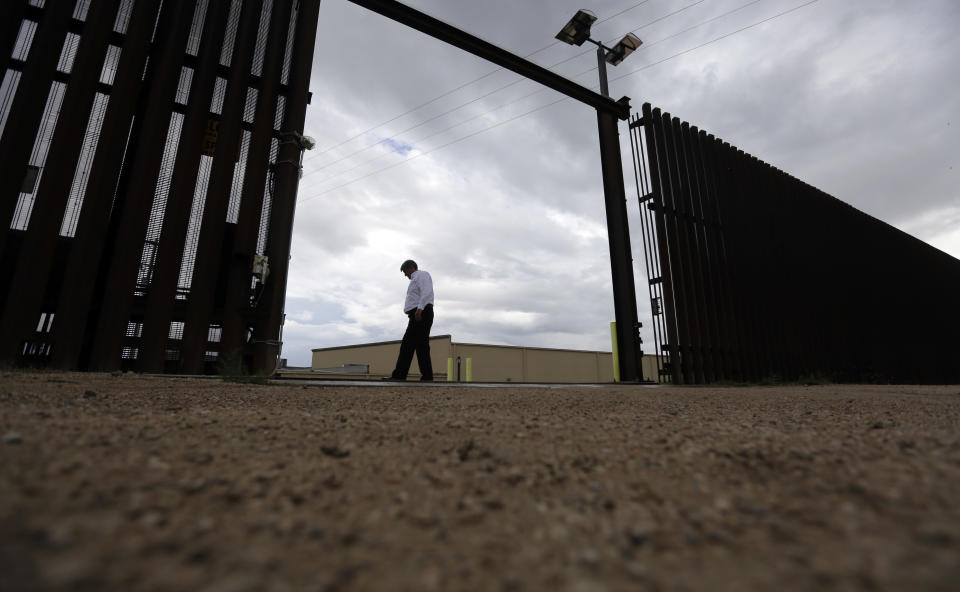 A worker for the Hidalgo County Water Improvement District walks along a gate in the border fence that runs along the water plant in Hidalgo, Texas. (Photo: Eric Gay/AP)