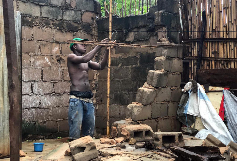 A man repairs a structure that collapsed due to heavy rains in Pemba, Mozambique, Sunday, April 28, 2019. Downpours began Sunday in parts of northern Mozambique that were hit by Cyclone Kenneth three days ago, with waters waist-high in areas, after the government urged many people to immediately seek higher ground. Hundreds of thousands of people were at risk. (AP Photo/Tsvangirayi Mukwazhi)