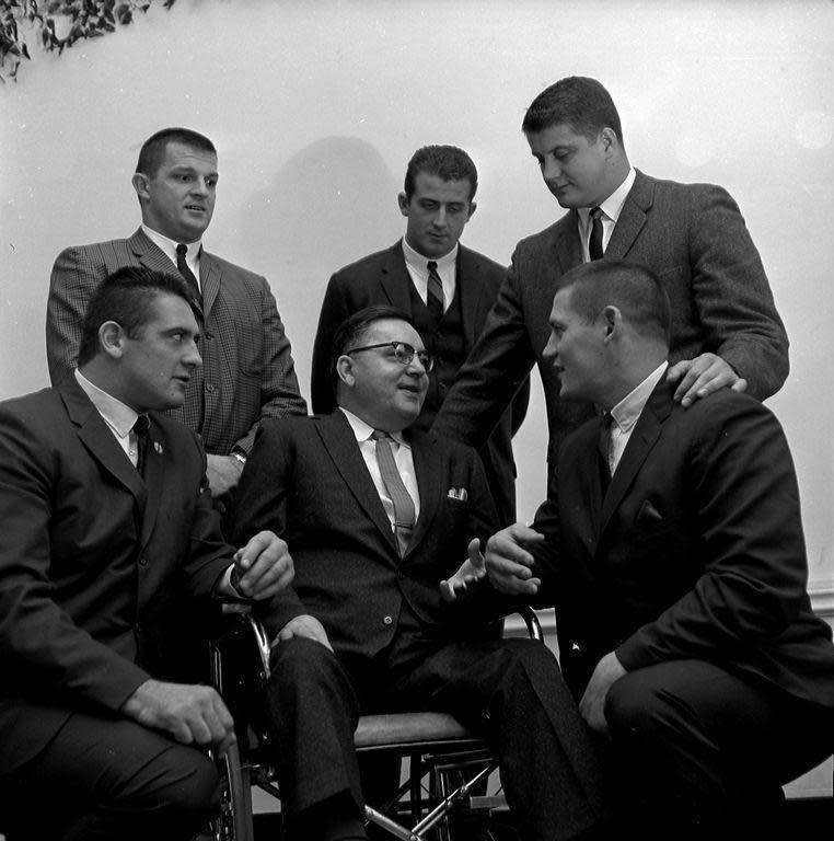 Five Cleveland Browns gather around Joe Corsey in 1964. Corsey was then secretary of the Canton Ex-Newsboys Association and is considered the father of the organization. The Browns players came to wish him luck in the 1964 fundraising newspaper sale and were guests at the Ex-Newsboys banquet at Onesto Hotel. Pictured are Corsey (center), surrounded by (left to right) Dick Schafrath (kneeling), Paul Wiggin, Gary Collins, Jim Houston, and Vince Costello (kneeling). The Ex-Newsboys gave the Browns a big ovation.