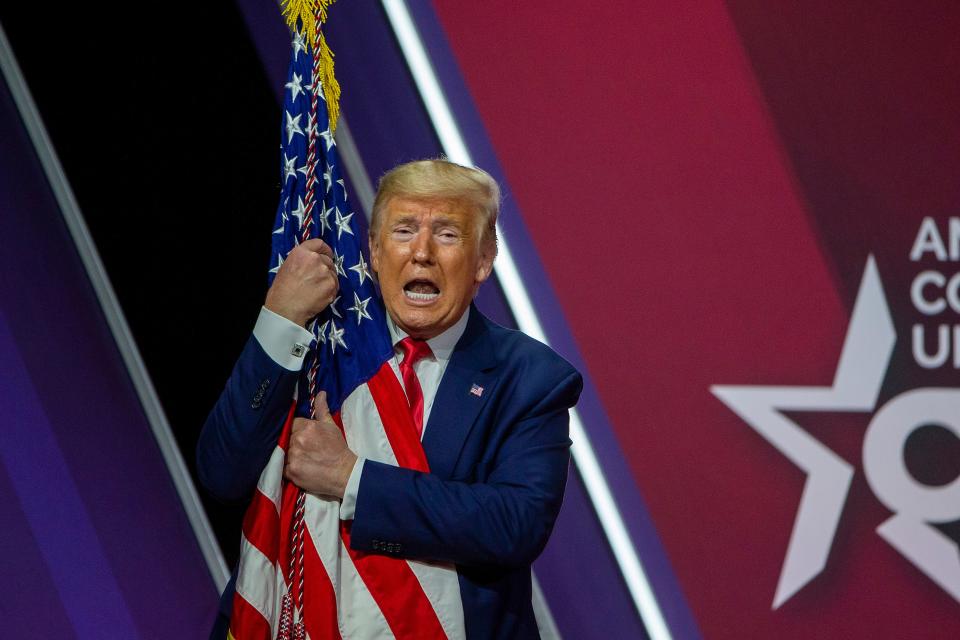 President Donald Trump hugs American flag at CPAC 2020