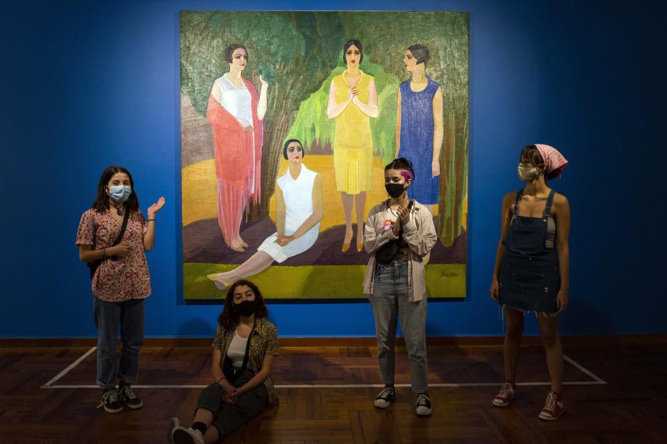 Amigos usando mascarillas contra el nuevo coronavirus posan para una foto en grupo frente a una pintura de Petrona Viera mientras visitan el Museo Nacional de Artes Visuales en Montevideo, Uruguay, el martes 4 de agosto de 2020. (AP Foto/Matilde Campodonico)