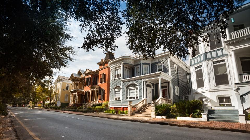 Tree lined historic homes on the community road in Savannah Georgia USA.