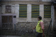 The Hindu symbol of well being Swastika is seen on a building as a Kashmiri man walks through a locality where many Kashmiri Hindu families used to live before the 1989 anti-India rebellion in Srinagar, Indian controlled Kashmir on Oct. 11, 2021. A spate of recent killings has rattled Indian-controlled Kashmir, with violence targeting local minority members and Indian civilians from outside the disputed region. The targeted killings have led to widespread unease, particularly among the region’s religious minority Hindus, most of whom fled Kashmir after an anti-India rebellion erupted in 1989. (AP Photo/Mukhtar Khan)