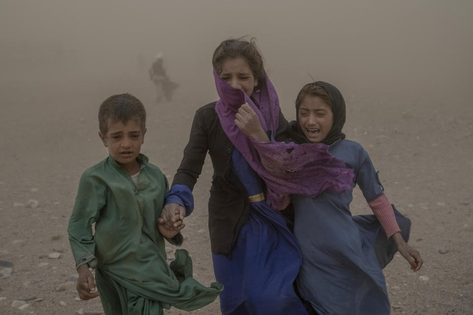 FILE- Afghan children carry donated aid to their tents, while they are scared and crying from the fierce sandstorm, after an earthquake in Zenda Jan district in Herat province, western of Afghanistan, Oct. 12, 2023. Almost 100,000 children direly need support three months after earthquakes devastated western Afghanistan, the U.N. children’s agency said Monday, Jan. 15, 2024. (AP Photo/Ebrahim Noroozi, File)